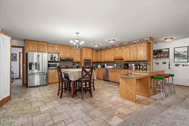 kitchen featuring a notable chandelier, tasteful backsplash, a kitchen bar, appliances with stainless steel finishes, and light tile floors