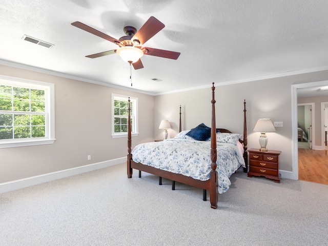 bedroom with carpet floors, ceiling fan, crown molding, and multiple windows