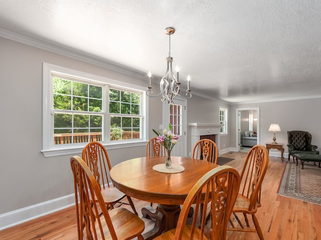 dining area featuring ornamental molding, light hardwood / wood-style flooring, a textured ceiling, and an inviting chandelier