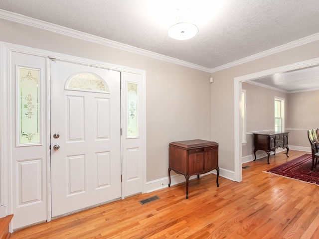 entryway with light hardwood / wood-style flooring, a textured ceiling, and crown molding