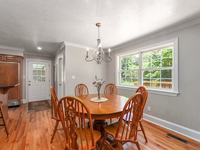 dining space with a chandelier, light hardwood / wood-style flooring, a textured ceiling, and crown molding