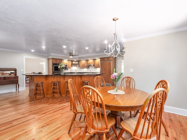 dining space with light hardwood / wood-style floors, a textured ceiling, ornamental molding, and ceiling fan with notable chandelier