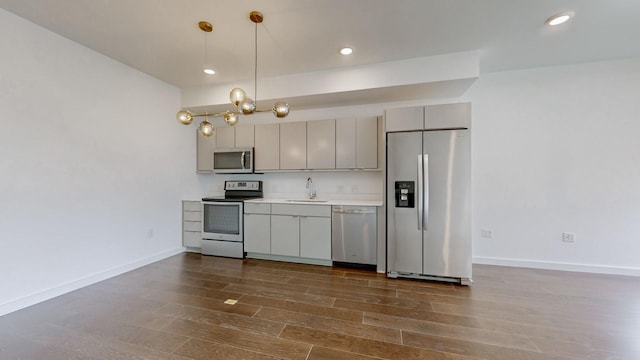 kitchen featuring sink, dark wood-type flooring, pendant lighting, gray cabinets, and appliances with stainless steel finishes