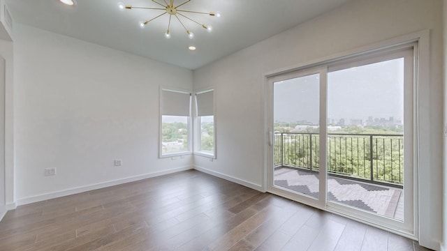 empty room featuring wood-type flooring and a notable chandelier