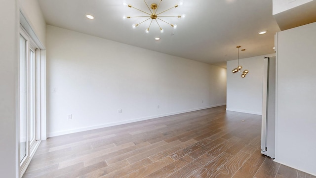 empty room featuring hardwood / wood-style flooring and a chandelier