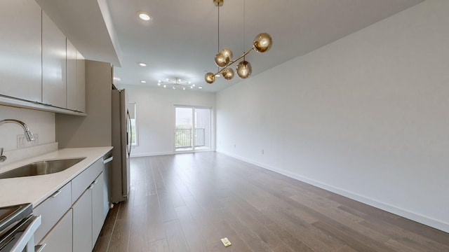 kitchen featuring pendant lighting, sink, light hardwood / wood-style flooring, appliances with stainless steel finishes, and a notable chandelier