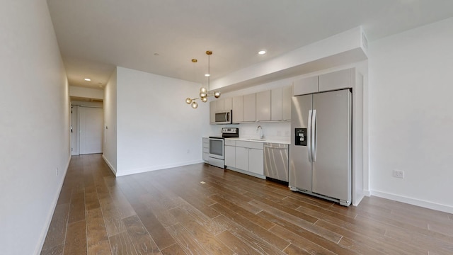 kitchen featuring appliances with stainless steel finishes, light hardwood / wood-style flooring, pendant lighting, and sink