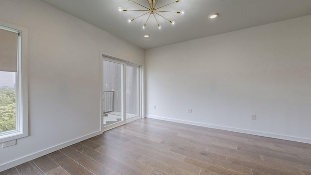 spare room featuring a chandelier and hardwood / wood-style floors