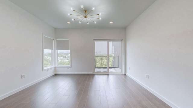 unfurnished room featuring hardwood / wood-style floors and an inviting chandelier