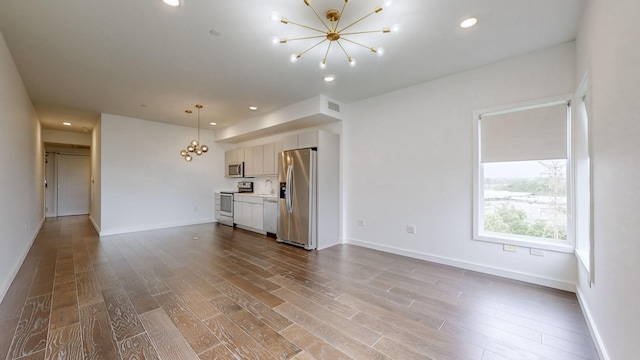 unfurnished living room featuring light hardwood / wood-style floors and a notable chandelier