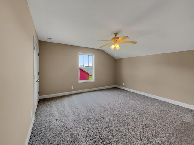 spare room featuring carpet, vaulted ceiling, and ceiling fan