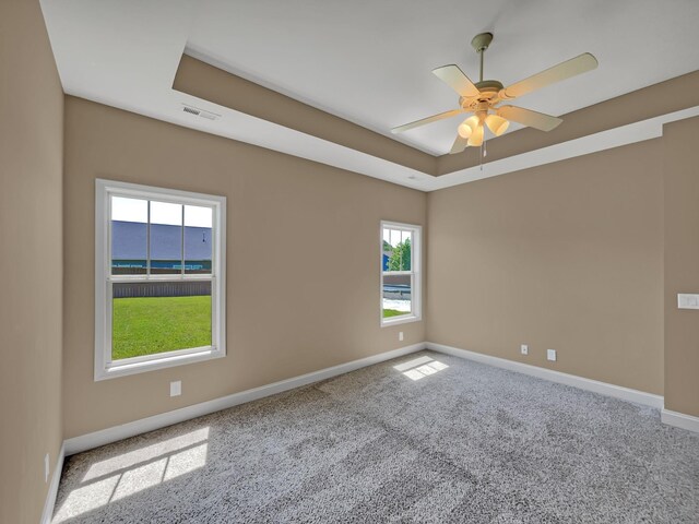 unfurnished room with carpet, a tray ceiling, and ceiling fan