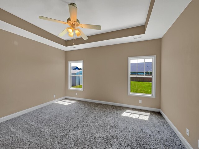 unfurnished room with carpet flooring, ceiling fan, and a tray ceiling