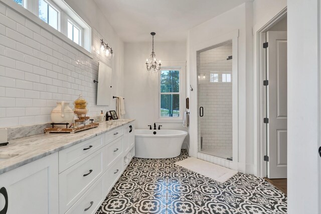 bathroom with decorative backsplash, tile patterned floors, vanity, separate shower and tub, and a notable chandelier