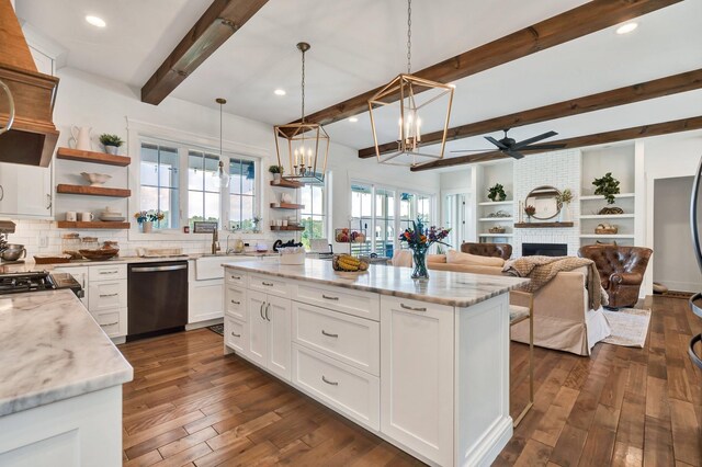 kitchen with light stone counters, a fireplace, dishwasher, white cabinetry, and hanging light fixtures