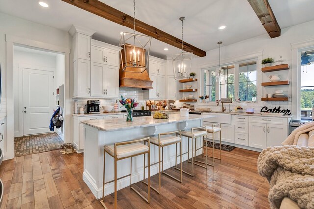 kitchen with beamed ceiling, a kitchen island, white cabinetry, and tasteful backsplash