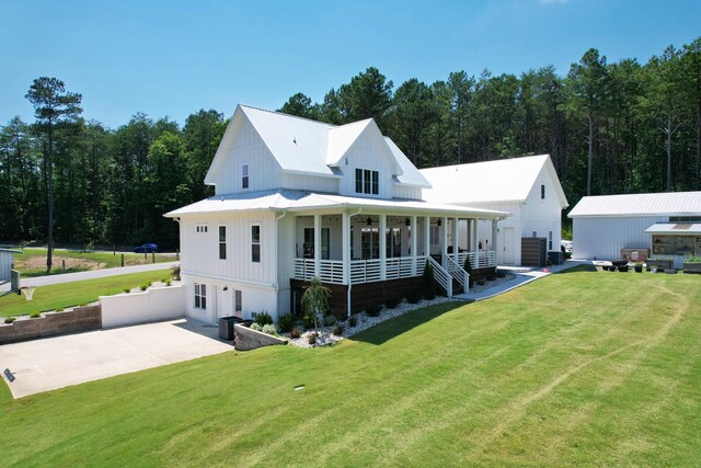 view of front facade featuring central AC unit, covered porch, and a front yard