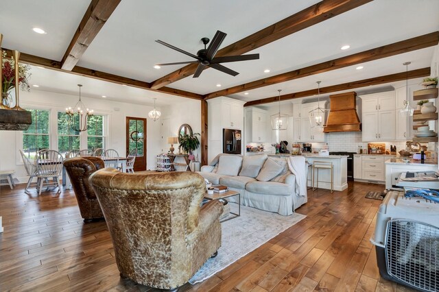 living room with beamed ceiling, dark hardwood / wood-style flooring, and ceiling fan with notable chandelier