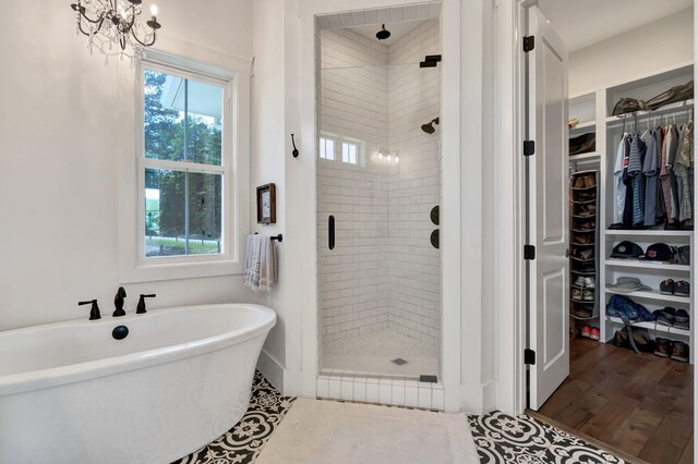 bathroom featuring a chandelier, hardwood / wood-style floors, and shower with separate bathtub