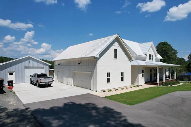 modern farmhouse style home with an outbuilding, a front lawn, covered porch, and a garage