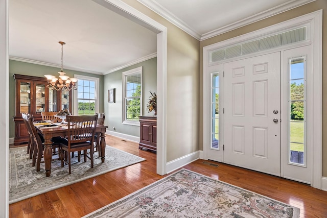 foyer featuring crown molding, wood-type flooring, and an inviting chandelier