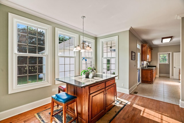 kitchen featuring ornamental molding, pendant lighting, an inviting chandelier, a center island, and light hardwood / wood-style floors