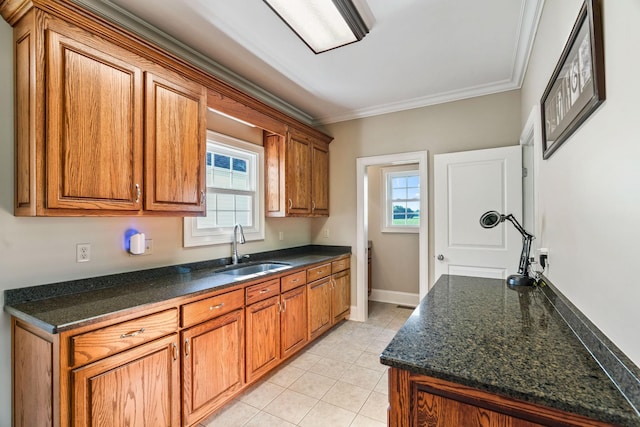 kitchen with ornamental molding, sink, light tile patterned floors, and dark stone counters