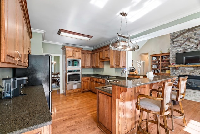 kitchen featuring kitchen peninsula, stainless steel appliances, light wood-type flooring, and ornamental molding