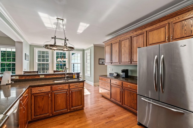 kitchen featuring stainless steel fridge, crown molding, sink, light hardwood / wood-style flooring, and hanging light fixtures