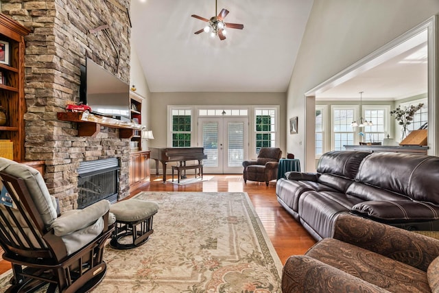 living room with a fireplace, french doors, high vaulted ceiling, and hardwood / wood-style floors