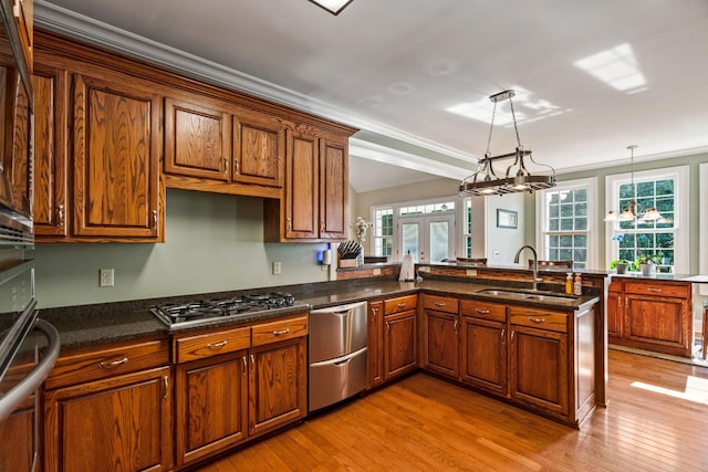 kitchen featuring stainless steel appliances, kitchen peninsula, sink, and pendant lighting