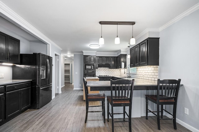 kitchen featuring tasteful backsplash, ornamental molding, a breakfast bar, sink, and black appliances