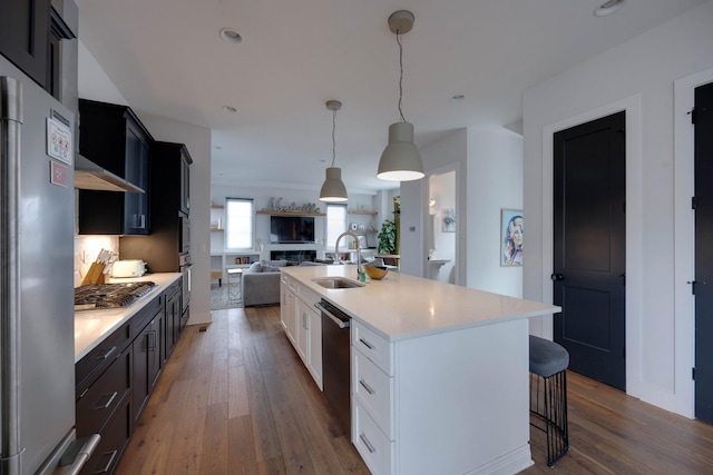 kitchen featuring sink, white cabinetry, hardwood / wood-style floors, stainless steel appliances, and an island with sink