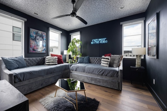 living room featuring ceiling fan, dark wood-type flooring, and a textured ceiling