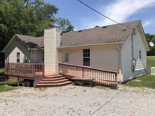 back of property with a deck, a chimney, and a shingled roof