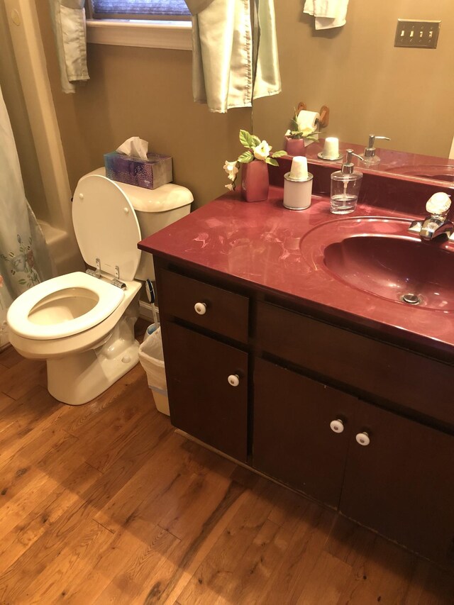 bathroom with hardwood / wood-style floors, vanity, toilet, and walk in shower