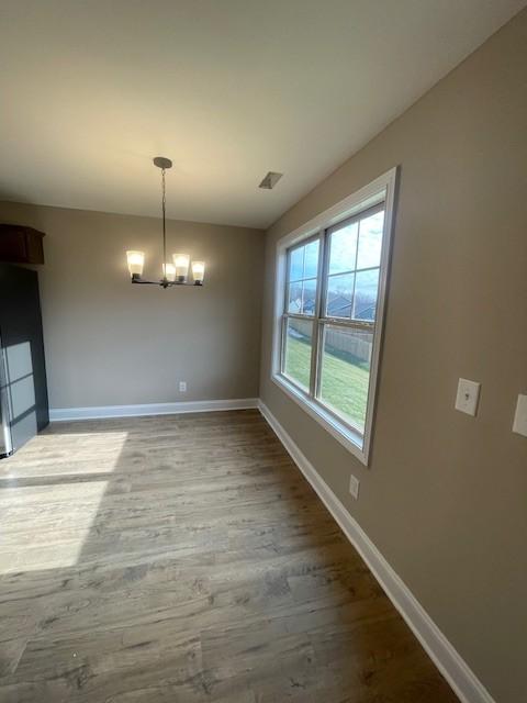 unfurnished dining area featuring a notable chandelier and hardwood / wood-style flooring