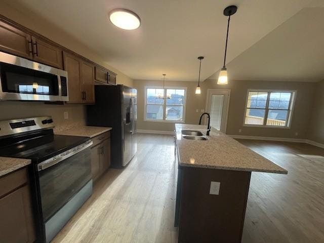 kitchen featuring light stone counters, sink, stainless steel appliances, and a kitchen island with sink