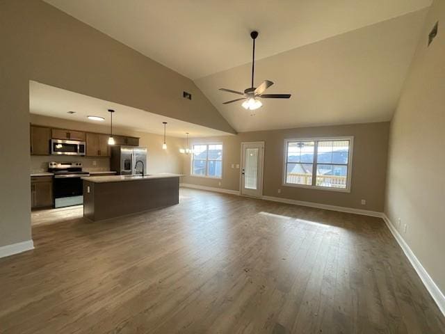 unfurnished living room featuring lofted ceiling, ceiling fan with notable chandelier, and dark hardwood / wood-style floors