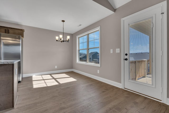 unfurnished dining area featuring a chandelier, wood finished floors, visible vents, and baseboards