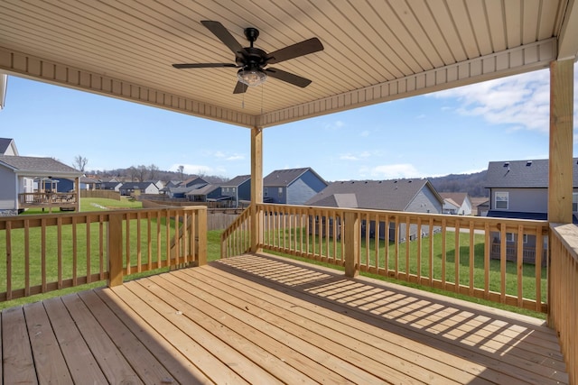 wooden terrace with ceiling fan, a residential view, and a yard