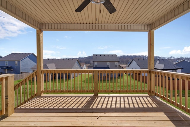 wooden terrace with a yard, a residential view, and a ceiling fan