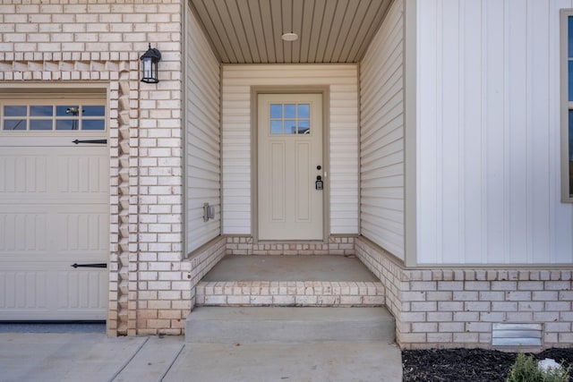 view of exterior entry with brick siding and an attached garage