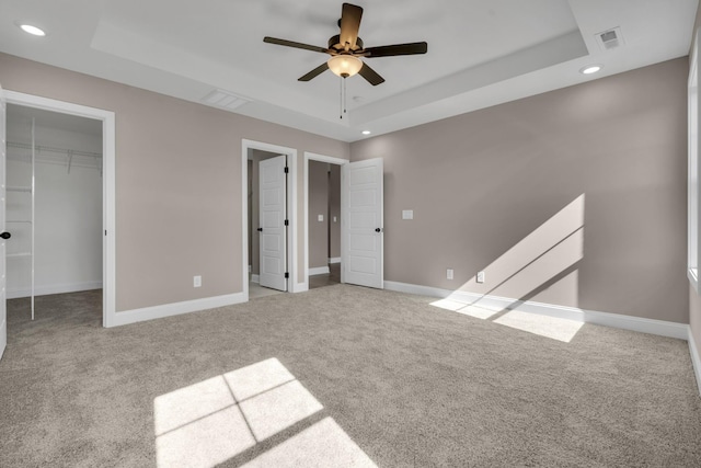 unfurnished bedroom with carpet floors, a raised ceiling, visible vents, and baseboards