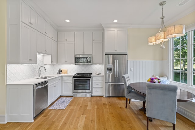 kitchen featuring light wood-type flooring, pendant lighting, backsplash, sink, and appliances with stainless steel finishes