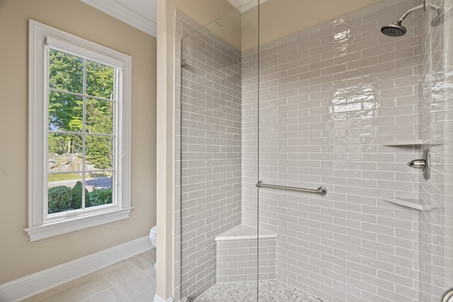 bathroom with a tile shower, plenty of natural light, toilet, and crown molding