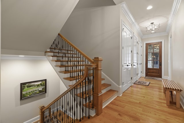 foyer entrance with a notable chandelier, ornamental molding, and light wood-type flooring