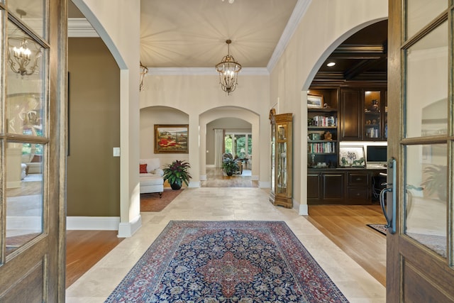 tiled entrance foyer with a notable chandelier, ornamental molding, and coffered ceiling