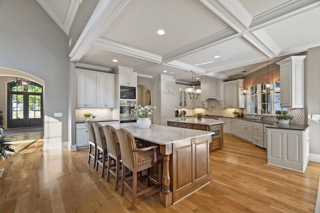 kitchen with light hardwood / wood-style floors, a kitchen island, light stone counters, pendant lighting, and tasteful backsplash