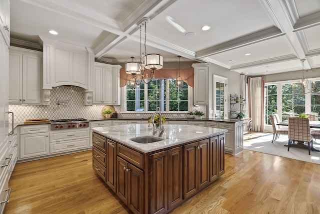 kitchen featuring light hardwood / wood-style floors, a center island with sink, stainless steel gas stovetop, sink, and pendant lighting